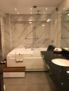 Baño blanco con bañera y lavamanos en Hotel Lexus, en Lima