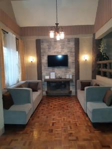 Zya 3BR A-House في باغيو: غرفة معيشة مع كنبتين وتلفزيون بشاشة مسطحة