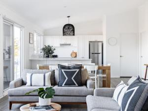 a living room with a couch and a kitchen at Ohana in Gerroa