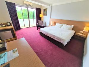 Merdeka Hotel Kluang في كلوانج: غرفة فندقية بسرير كبير وكرسي