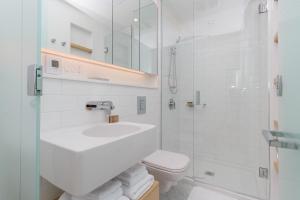 a white bathroom with a sink and a toilet at Historic Waterside With Spectacular Johnson Bridge Views in Victoria +23 photos