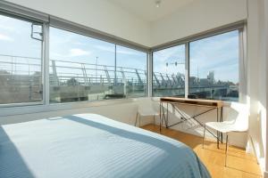 a bedroom with a bed and a desk and windows at Historic Waterside With Spectacular Johnson Bridge Views in Victoria