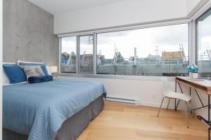 a bedroom with a bed and a desk and a window at Historic Waterside With Spectacular Johnson Bridge Views in Victoria