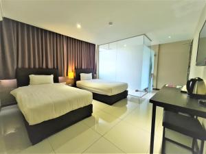 a hotel room with two beds and a desk at Merdeka Hotel Kluang in Kluang