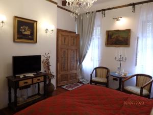 a bedroom with a bed and a television and a table at Casa Cositorarului Boutique Pension in Sighişoara