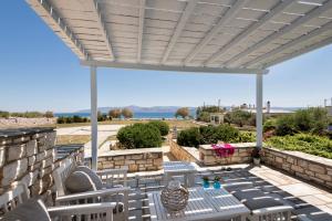 a patio with chairs and a table and a white pergola at Ambelas Mare Apartments in Ambelas