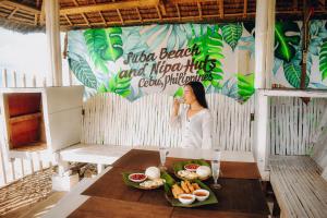 a woman talking on a cell phone at a table with food at Suba Beach Nipa Huts in Daanbantayan +37 photos