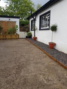 a driveway next to a house with two potted plants at The little garden hoose in Inverness