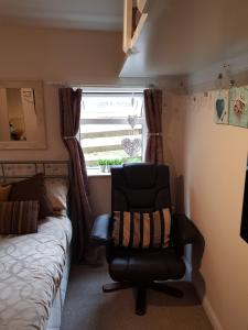 um quarto com uma cadeira, uma cama e uma janela em The little garden hoose em Inverness