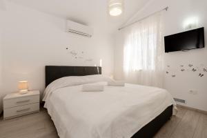 a white bedroom with a large bed and a flat screen tv at Villa Rose in Kršan