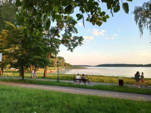 mensen op een bankje bij het water bij Apartament MIŁOSZA in Ełk