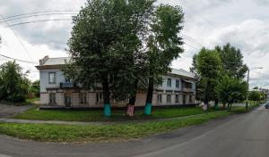 a building with a tree in front of a street at Апартаменты у Вокзала in Prokop'yevsk