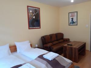 a bedroom with a bed and a couch and a table at Macskafogo, tunderi szallas a belvarosban in Győr