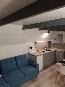 un salon avec un canapé bleu dans une cuisine dans l'établissement domek good vibes A, à Gnieżdżewo