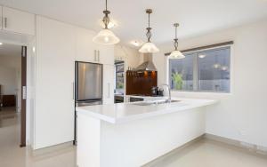 a white kitchen with a sink and a refrigerator at Luxury Retreat with Swim Spa in Taupo