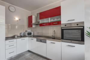 una cocina con electrodomésticos blancos y armarios rojos en M & M Apartment, en Pula