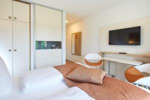 1 dormitorio con 1 cama y TV en la pared en VR-Serviced Apartments Obergeis en Neuenstein