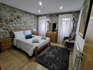 a bedroom with a bed and a stone wall at Isabel do Couto - casa de charme in Castro Daire