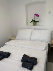 a white bed with two black towels on it at Dália apartman Gyömrő in Gyömrő