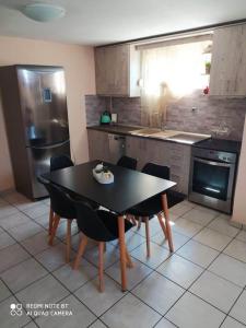 uma cozinha com uma mesa preta e cadeiras e uma cozinha com um frigorífico em Chrysa Mare em Kavala