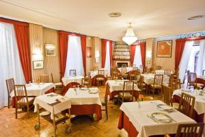 un restaurant avec des tables et des chaises blanches et des rideaux rouges dans l'établissement Hotel Moderno, à Erice