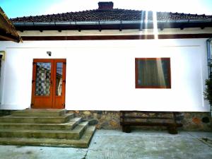 une maison blanche avec une porte rouge et des escaliers dans l'établissement Casa Petrescu, à Curtea de Argeş