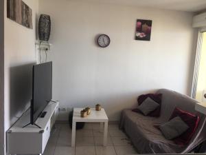 a living room with a couch and a clock on the wall at Les Balcons de la Mer in Valras-Plage