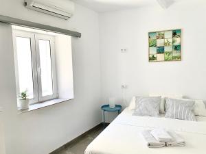 een witte slaapkamer met een bed en een raam bij Easy Nerja House in Nerja