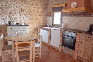 a kitchen with a table and a stove and a sink at Casa Rural El Morral in La Mata de los Olmos