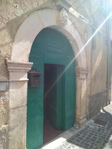 un arco en un edificio con una puerta verde en villagiannina, en Teggiano