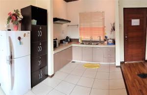 eine Küche mit einem weißen Kühlschrank und einem weißen Fliesenboden in der Unterkunft Teaz Apartment @ Iris House Resort in Cameron Highlands