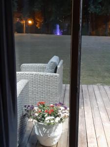 eine Terrasse mit 2 Korbstühlen und einer Kanne Blumen in der Unterkunft Mazoji vila in Birštonas