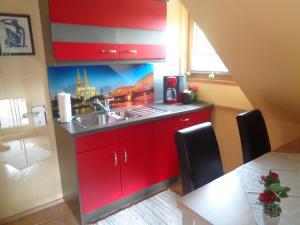 cocina con armarios rojos, fregadero y mesa en Ferienwohnung Carmen en Siegen