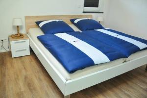 a large bed with blue and white sheets and pillows at Ferienwohnung „Zum Leuchtturm“ in Großdubrau