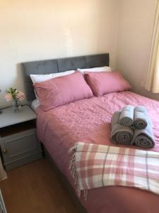 um quarto com uma cama rosa e toalhas em Chalet18 em Carmarthen