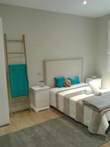 a bedroom with two beds with blue pillows and a ladder at Alquiler Aptos en Santander (Centro) in Santander