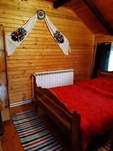 ein Schlafzimmer mit einem roten Bett in einem Holzzimmer in der Unterkunft Cabana La Mariuca in Borsa