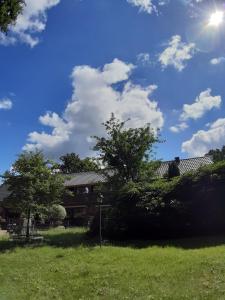 a house in a yard with the sun in the sky at Pension Im Rehwinkel in Soltau