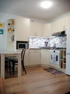 a kitchen with white cabinets and a table with chairs at Slávik Apartment in Dunajská Streda