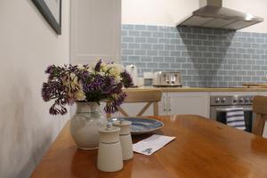 a vase with flowers on a wooden table in a kitchen at Victoria Cottage in Robe +10 photos