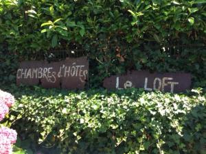 two signs in a bush with flowers at Loft Atypique in Villeneuve-de-Rivière