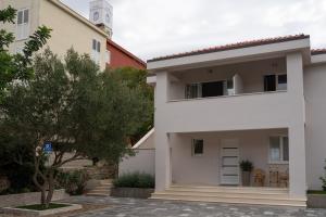 uma casa branca com uma árvore em frente em Korkyra Fit suites -free gym em Korčula