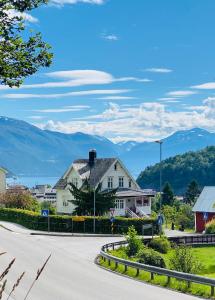 a house on a street with mountains in the background at Fjord View Apartment in Stranda
