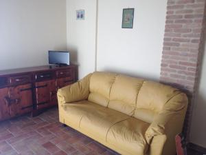 a couch sitting in a living room with a tv at La Locanda Del Colle in Canalicchio