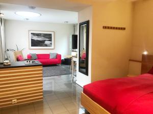 ケルンにあるbel xantoのベッドルーム1室(赤いベッド1台付)、リビングルームが備わります。
