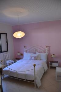 a bedroom with a bed with white sheets and a pink wall at Villa Physis in Parga