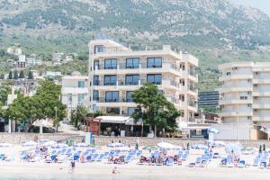 uma praia com cadeiras e um grande edifício em Sunset Hotel & Beach em Dobra Voda