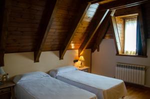 two beds in a room with wooden ceilings at Albares in Vielha