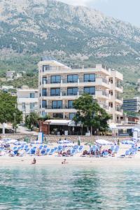 a hotel on a beach with chairs and the water at Sunset Hotel & Beach in Dobra Voda