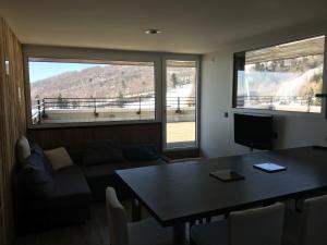 a living room with a table and a couch and windows at Appartement au pied des pistes in Besse-et-Saint-Anastaise